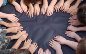 Kindergarten students put their hands together in the shape of a heart